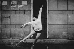graceful dancer performing on street standing in puddle