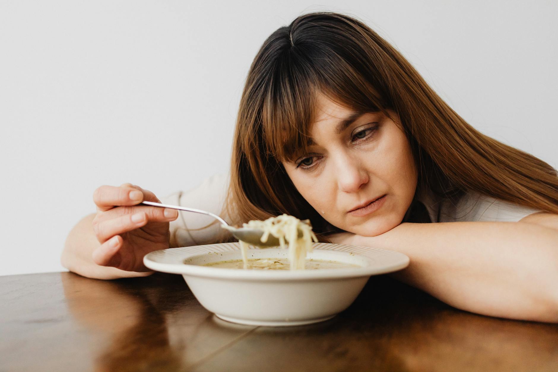close up of a sad woman eating soup
