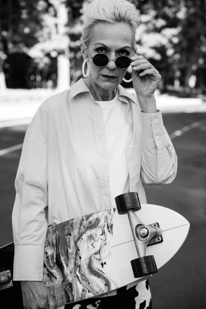 an elderly woman in sunglasses holding a skateboard