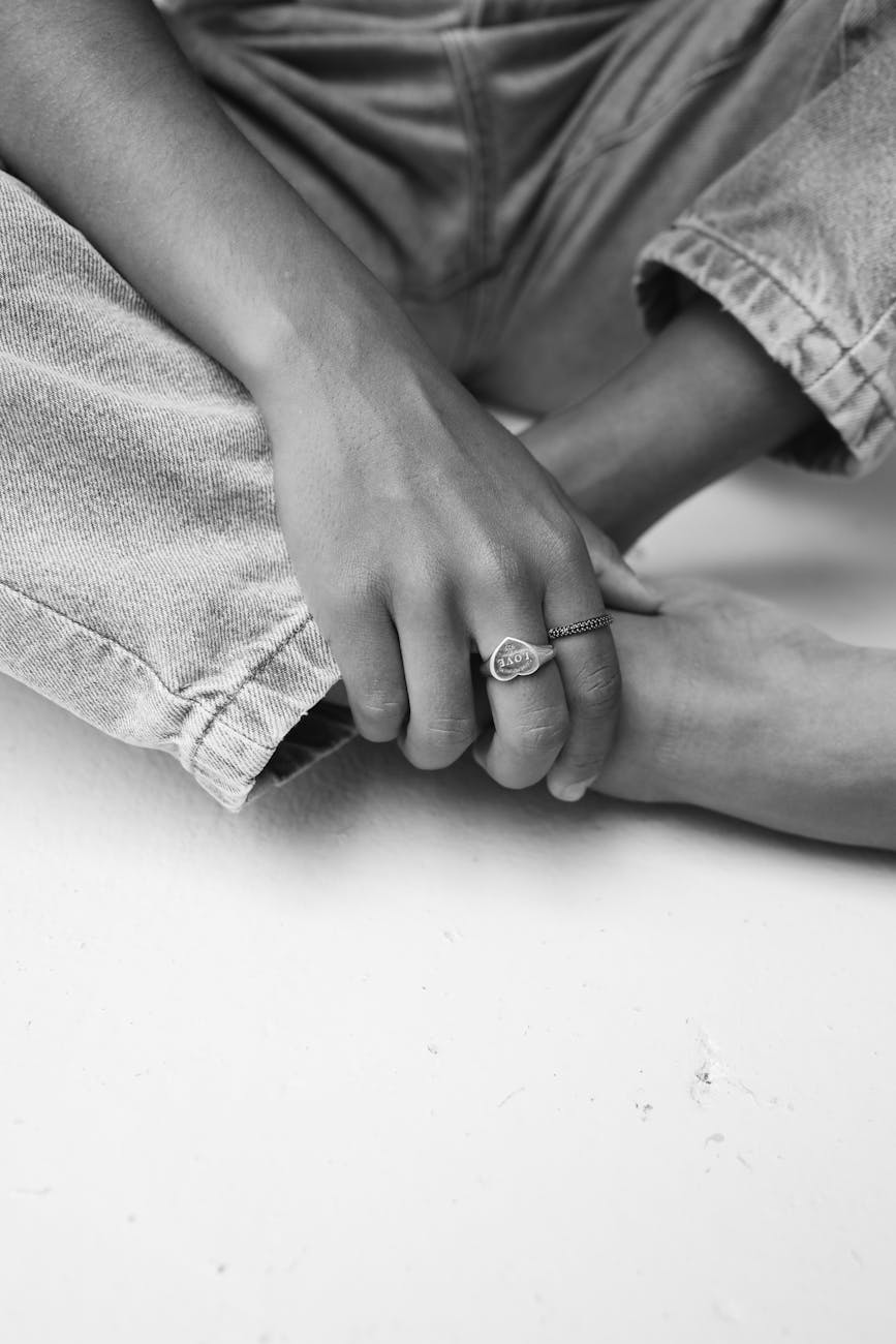 a hand with rings crossed over legs